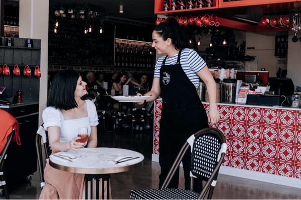 A waiter serving a woman a crepe outside the restaurant